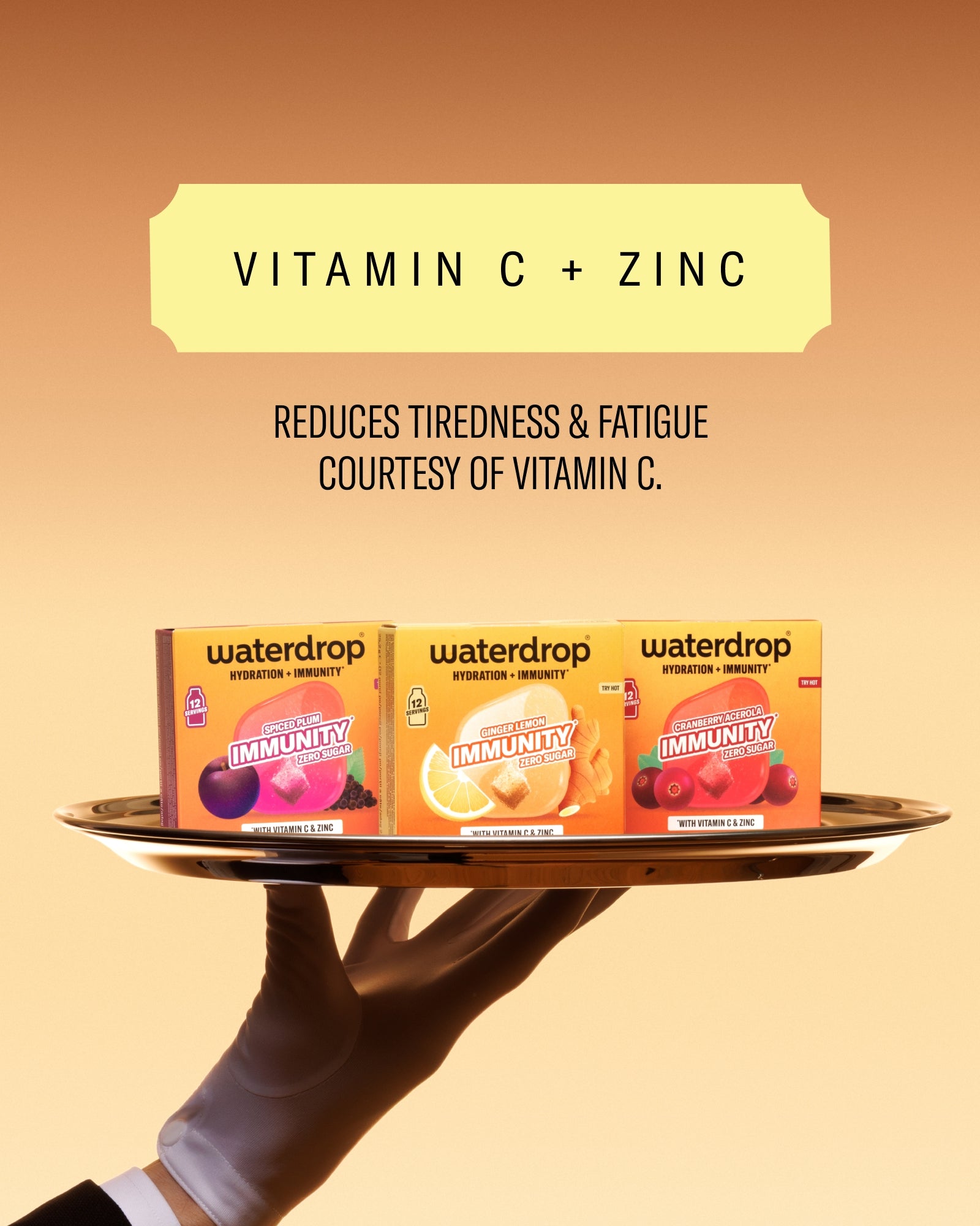Tri kutije vitamina na okrugloj plohi koje drži gloved ruka na pozadini narandžaste gradijente.