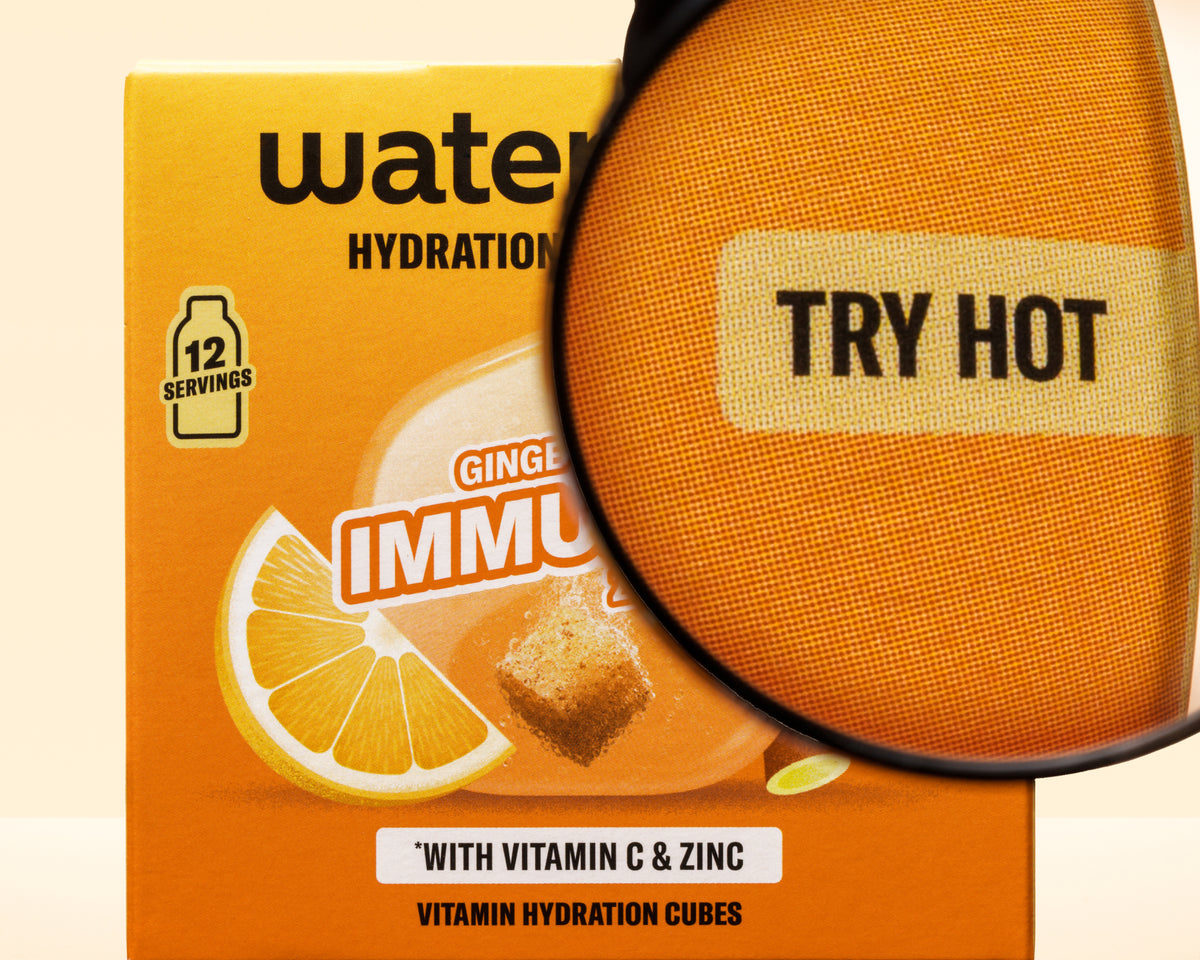 Narančasta kutija s grafikom limuna i povećalom preko nje, promocija vitaminskih kockica za hidrataciju.